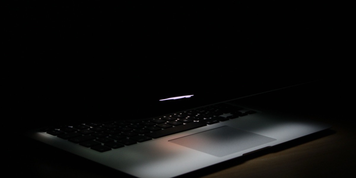 A sleek laptop glowing softly in a dark, minimal workspace