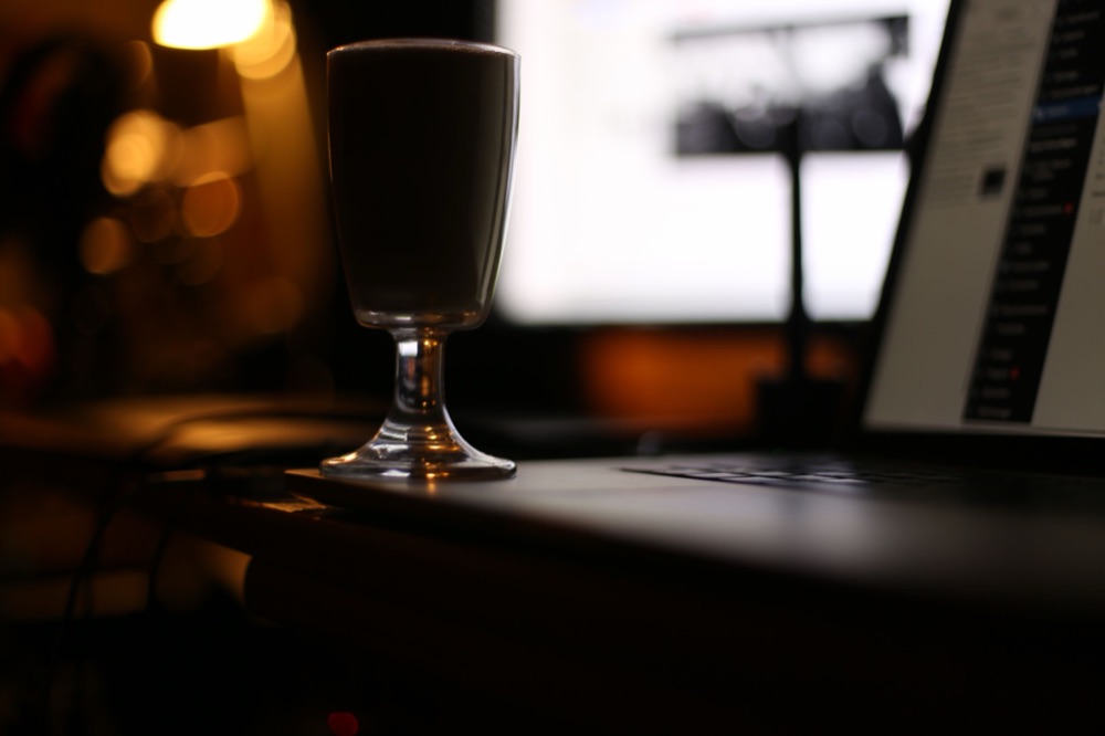 A moody, low-lit desk with a laptop and a glass
