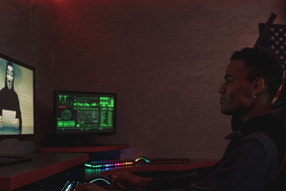 A security analyst monitoring data on screens in a dark room
